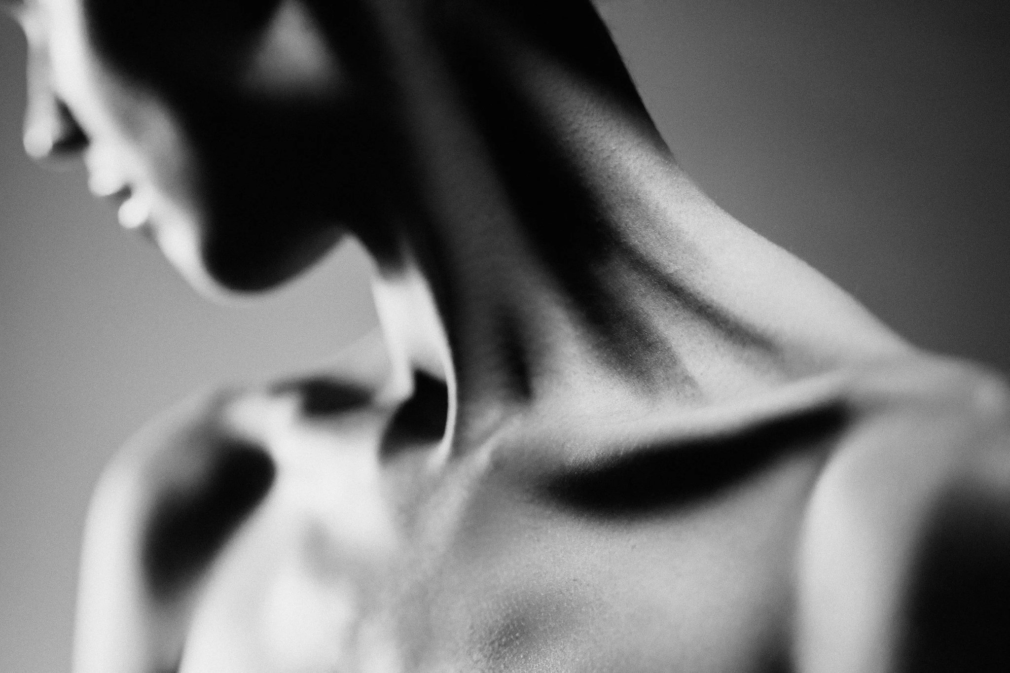 Black-and-white study of a person’s neck and shoulders, head turned away.